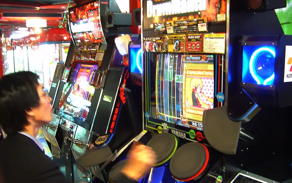 Player concentrating on a colorful arcade cabinet with flashing lights