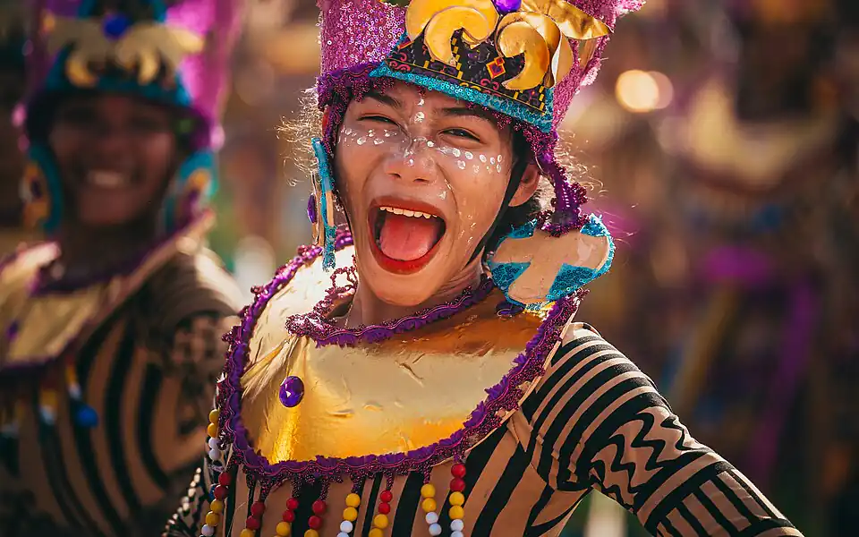 Smiling Filipino festival dancer in a bright costume at Sinulog, the fiesta energy behind every color game perya